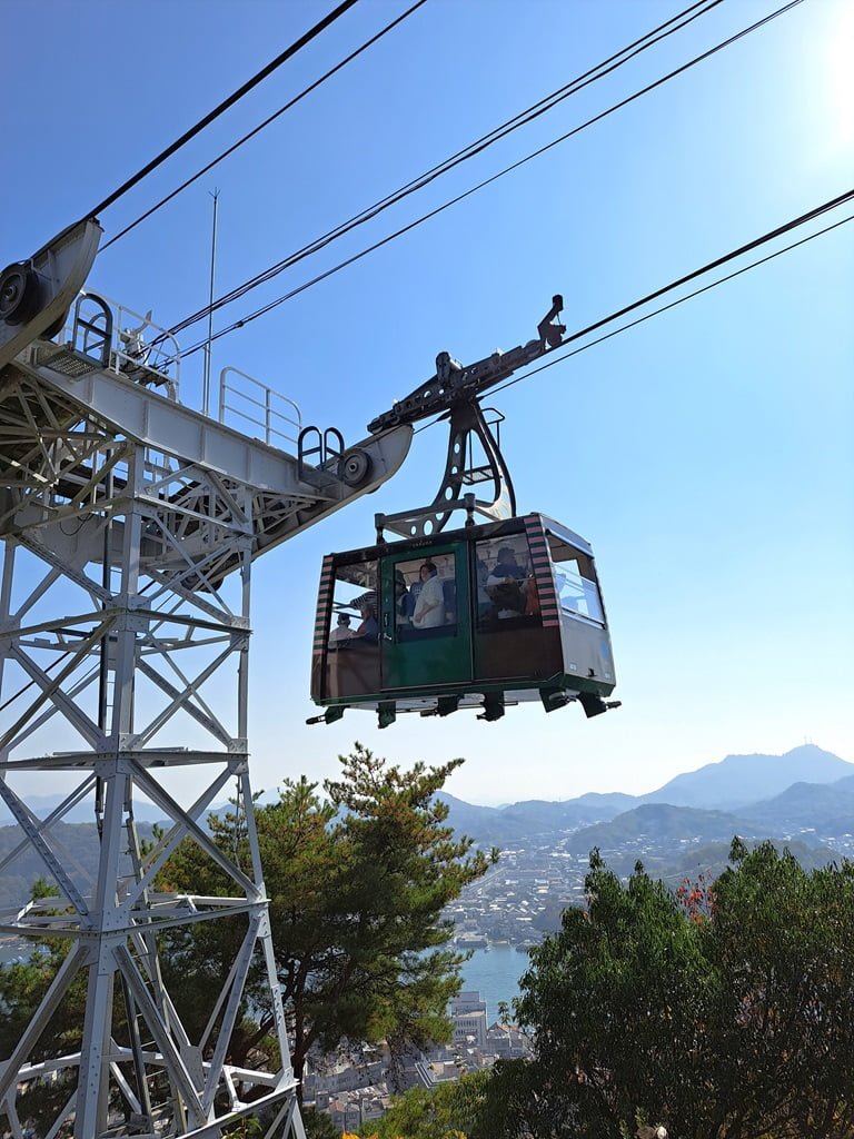 【廣島】尾道一日遊-讓人一眼就愛上的山城小鎮、水道與瀨戶內海 - 第69張圖 一旁緩緩經過的纜車